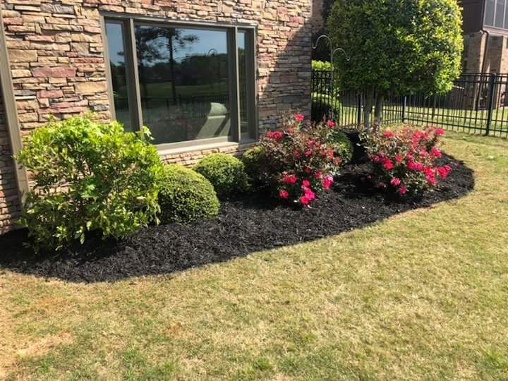 A garden with flowers and bushes in front of a house.