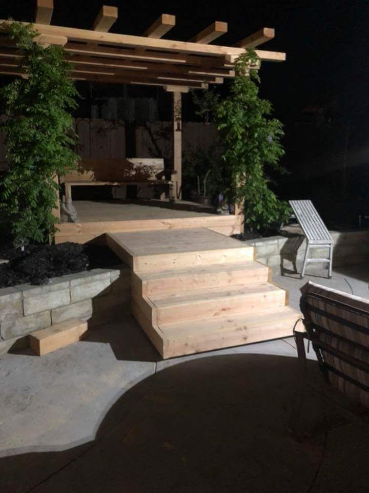 A patio with a pergola and stairs at night
