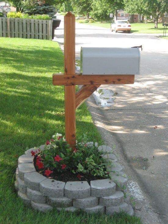 A mailbox is sitting in the grass next to a stone planter