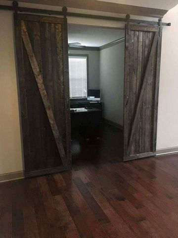 A room with sliding barn doors leading to a home office.