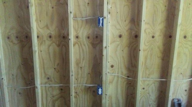 A close up of a wooden wall with electrical wires coming out of it.