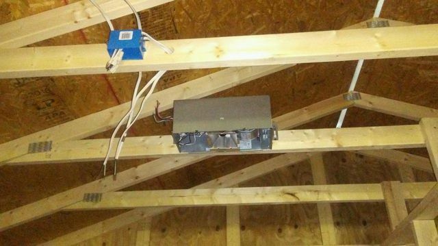 A box is hanging from the ceiling of a building under construction.