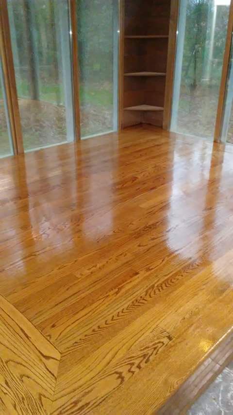 A wooden floor in a room with lots of windows and shelves.