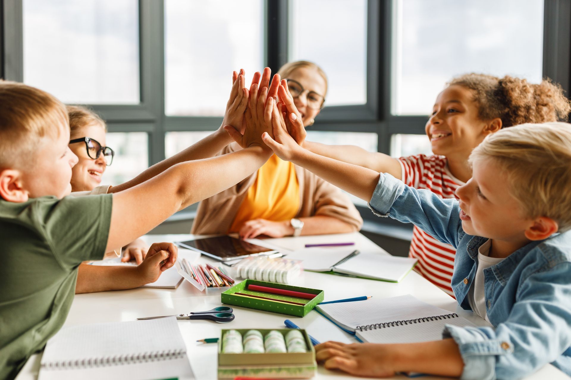 Kids classroom with group of students giving a high-five