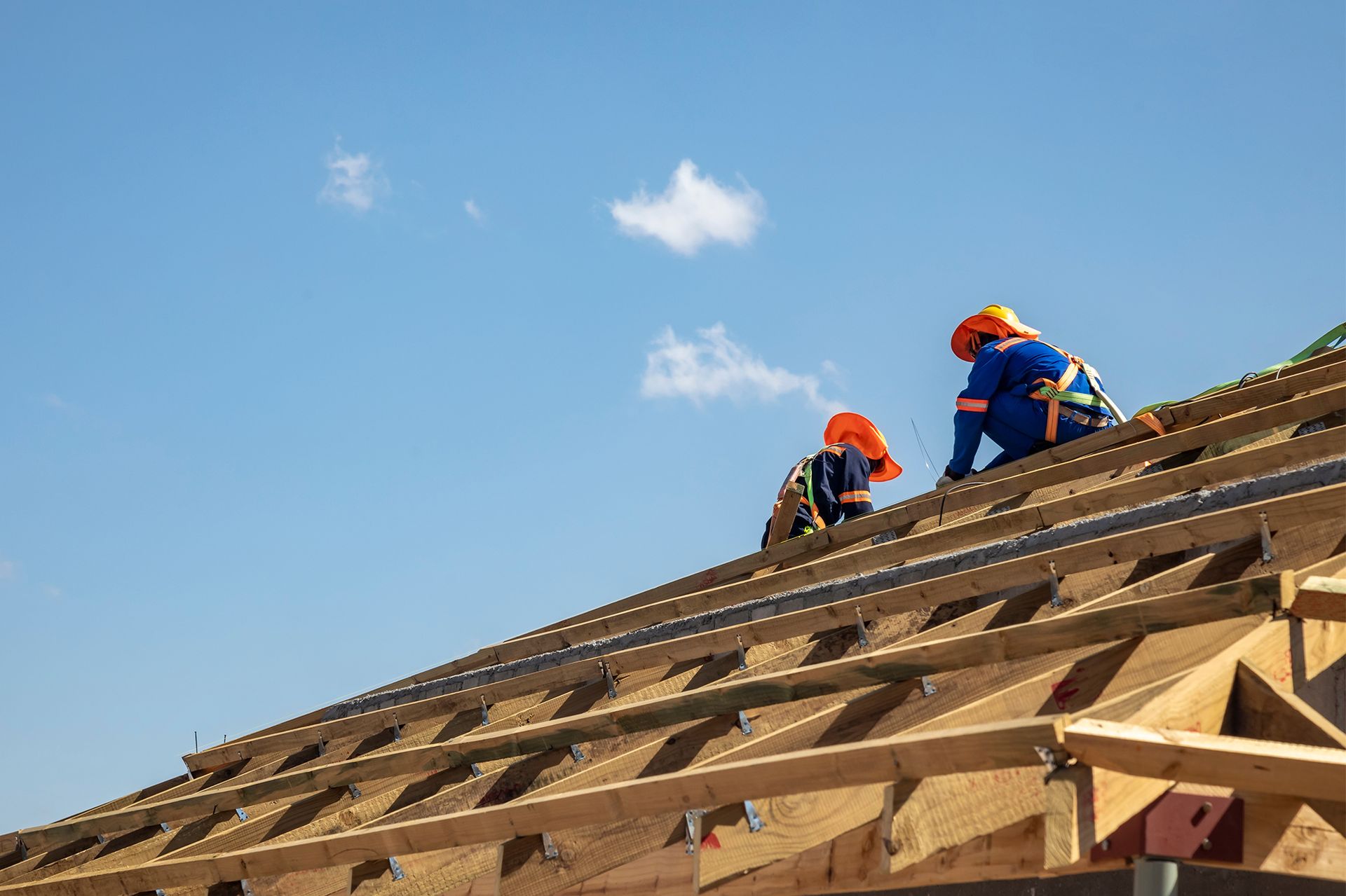 Two construction workers are working on a wooden roof.