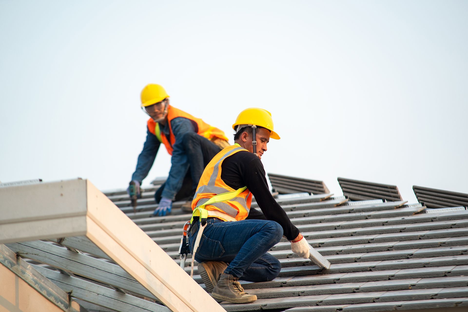 Two construction workers are working on the roof of a building.