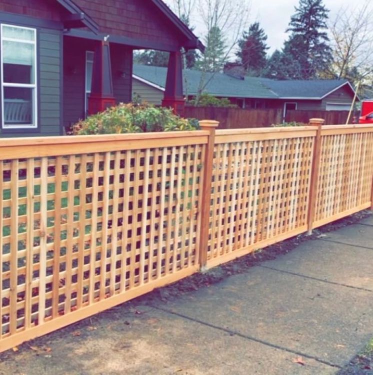 A wooden lattice fence along a sidewalk in front of a house