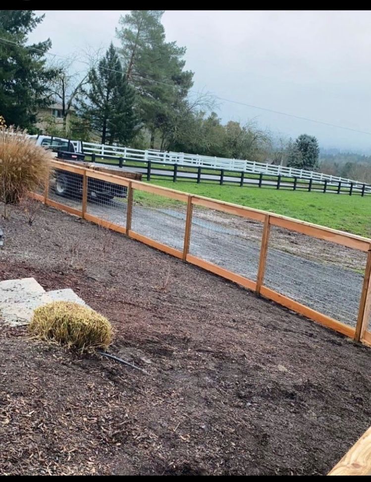 A wooden fence surrounds a dirt road and a field.