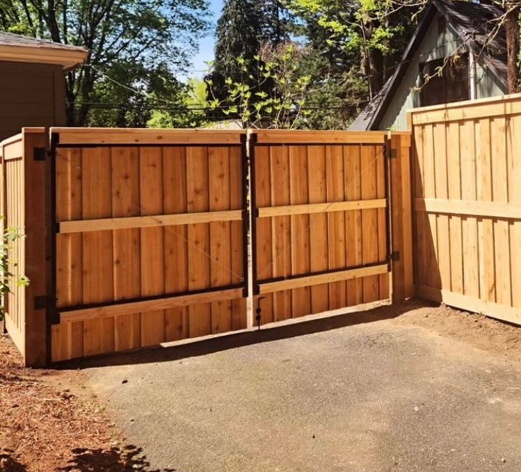 A wooden fence surrounds a driveway in front of a house