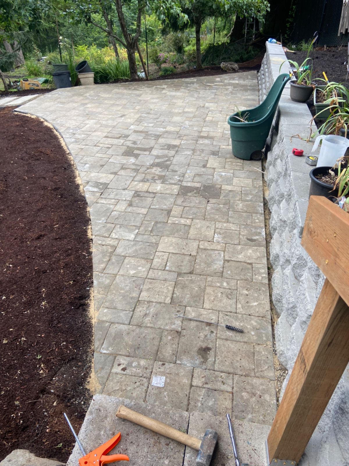 A brick walkway with a hammer and pliers on the side of it.