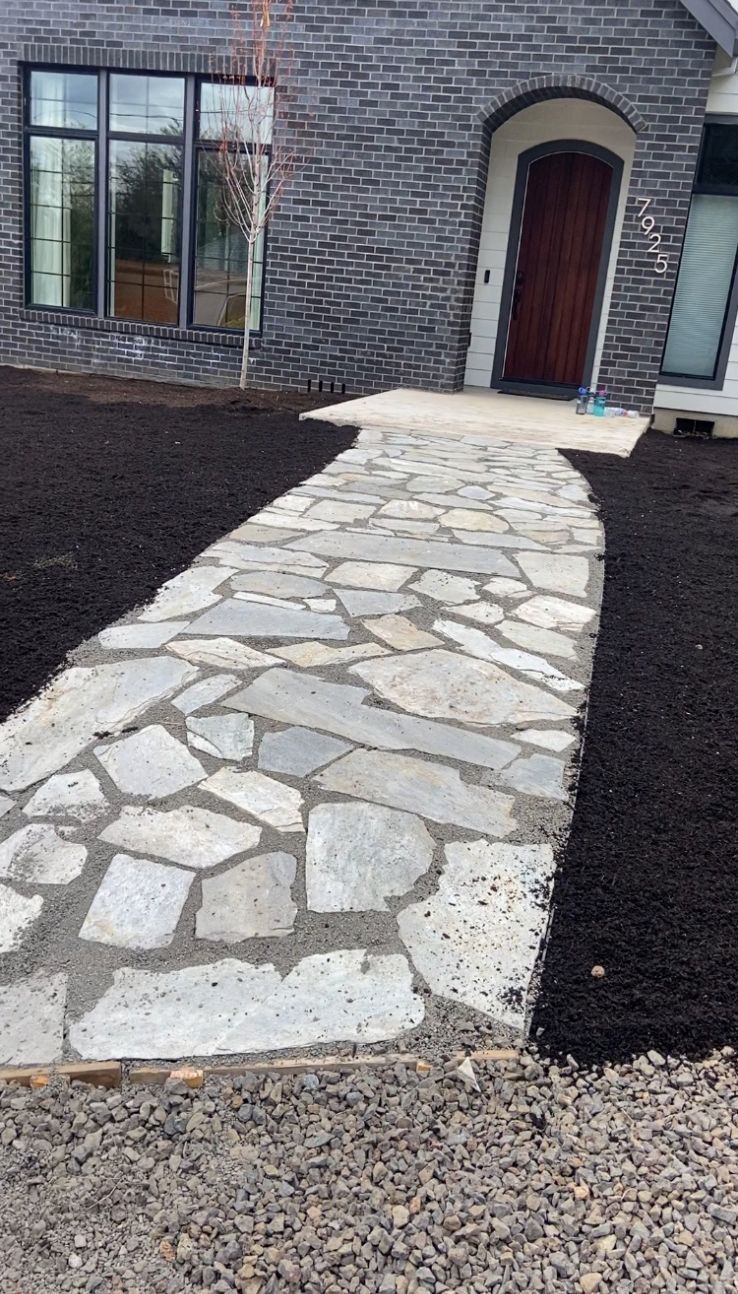 A stone walkway leading to the front door of a brick house.