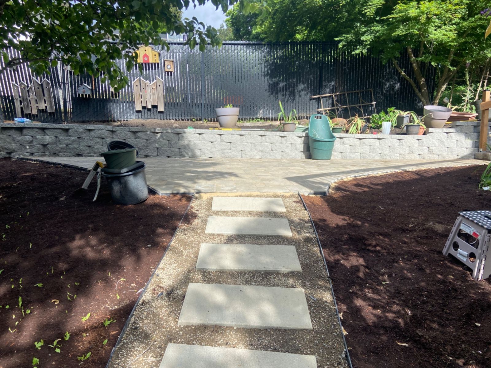 A stone walkway leading to a fenced in backyard