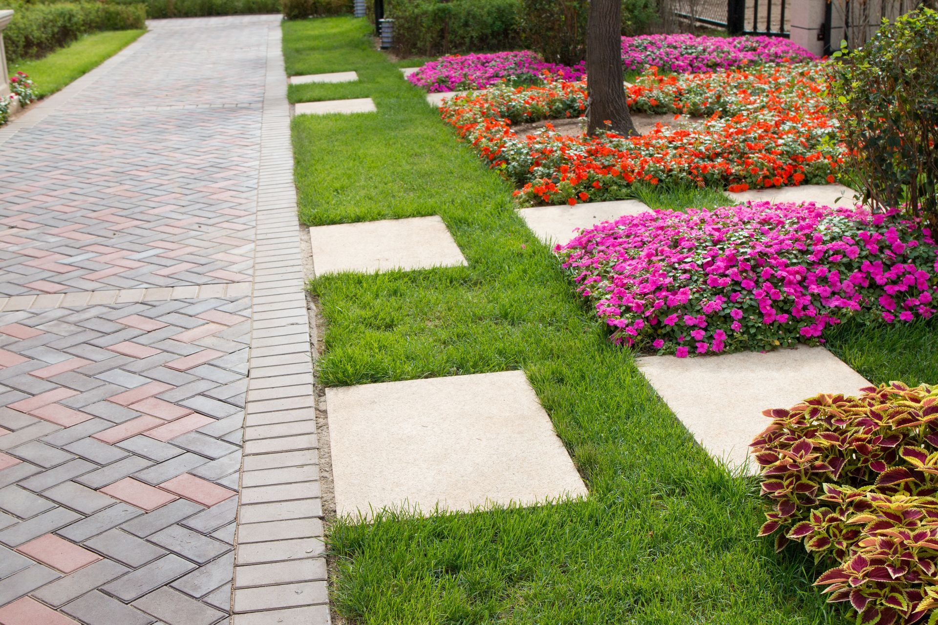A brick walkway surrounded by flowers and grass