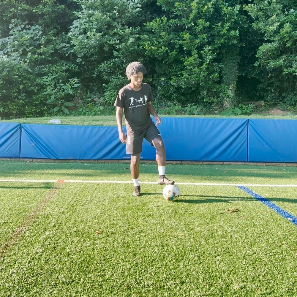 A boy wearing a shirt that says just kicks a soccer ball