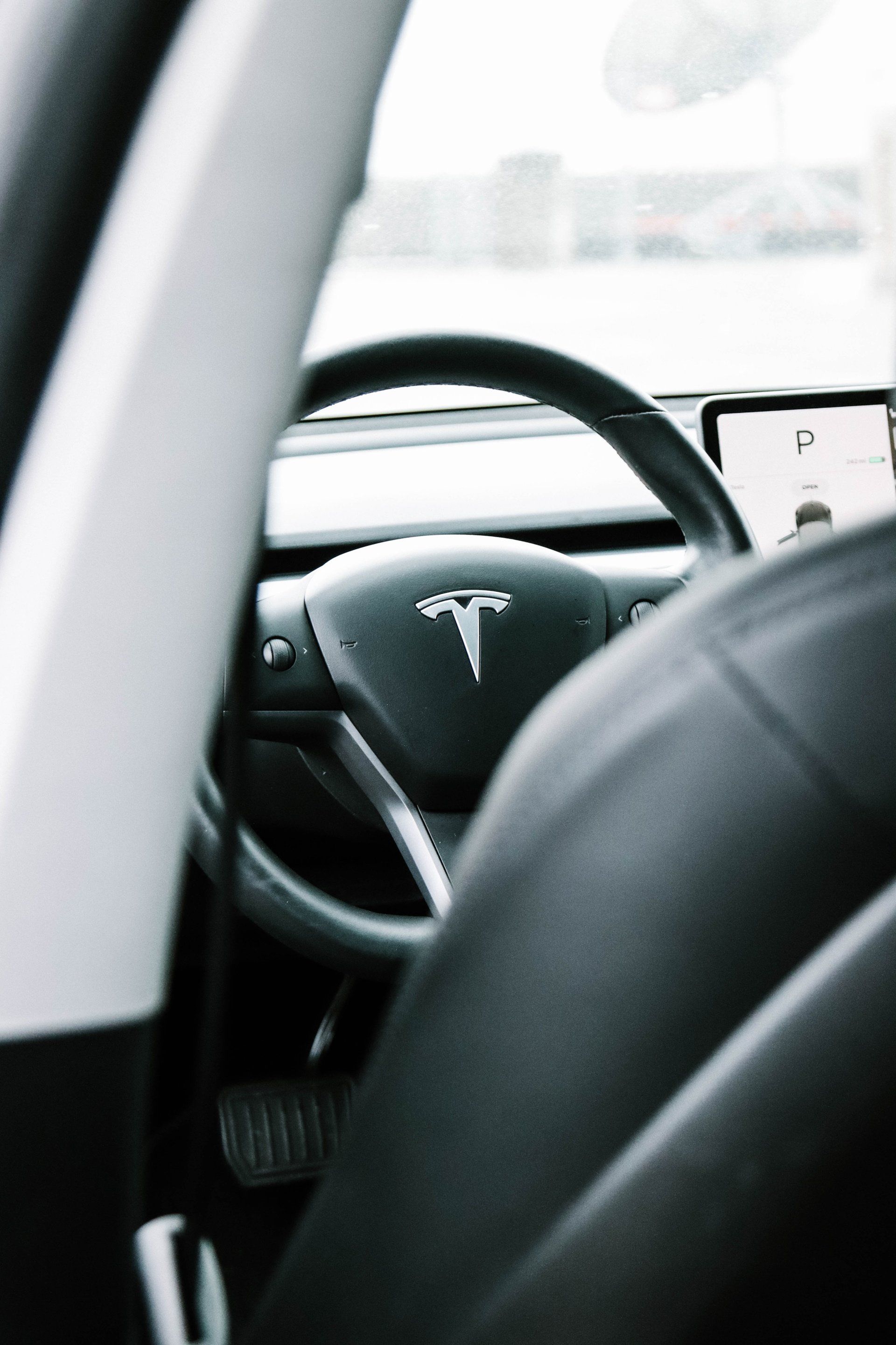 A close up of a tesla model 3 steering wheel and seat.