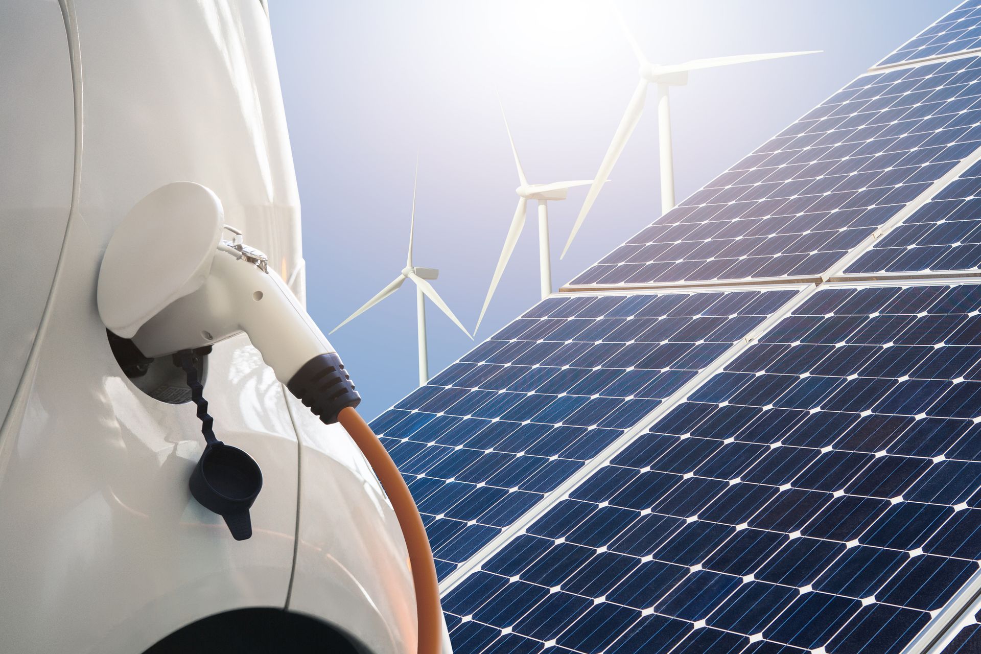 An electric car is being charged by solar panels and wind turbines.