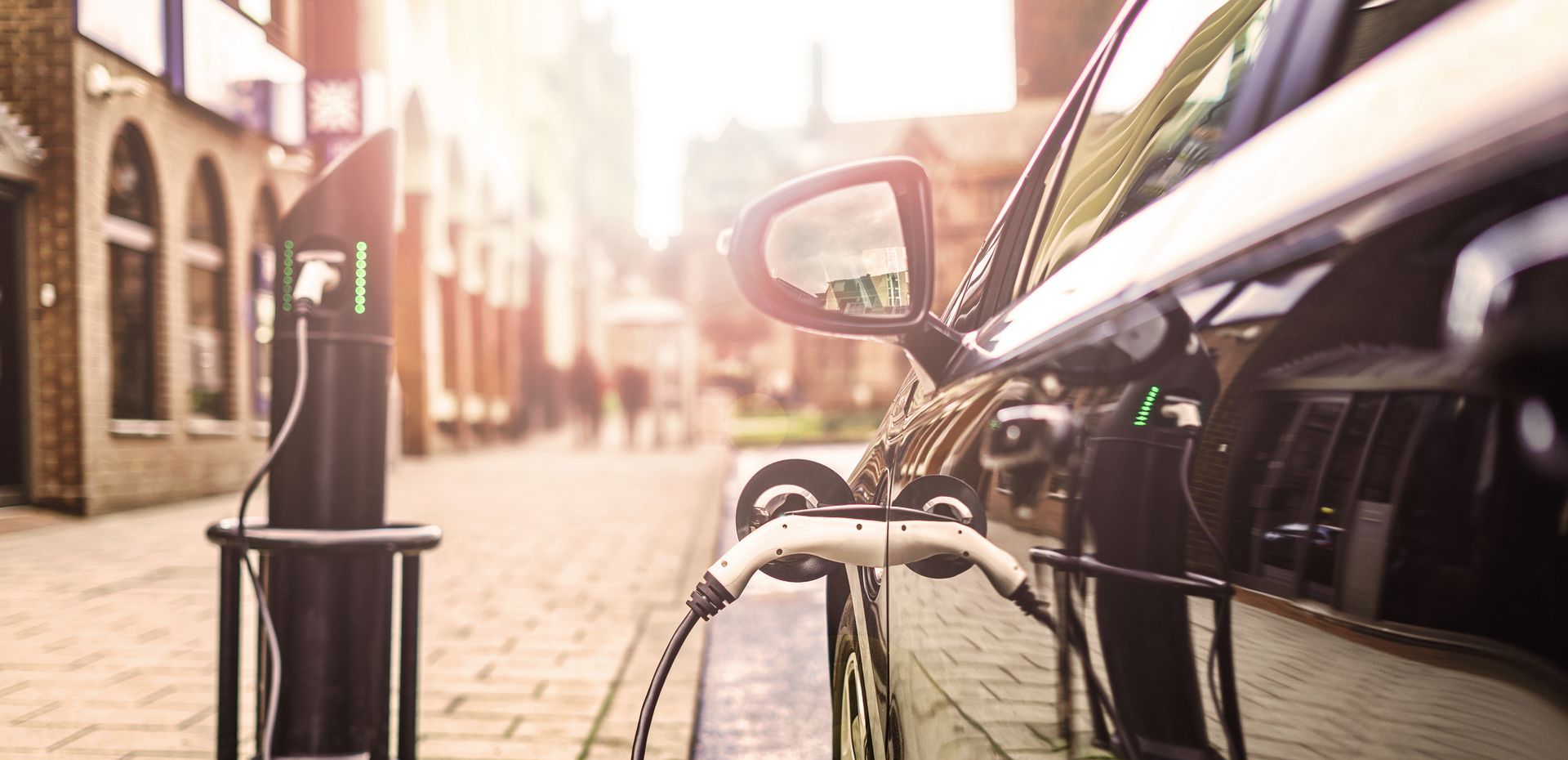 An electric car is being charged at a charging station on a city street.