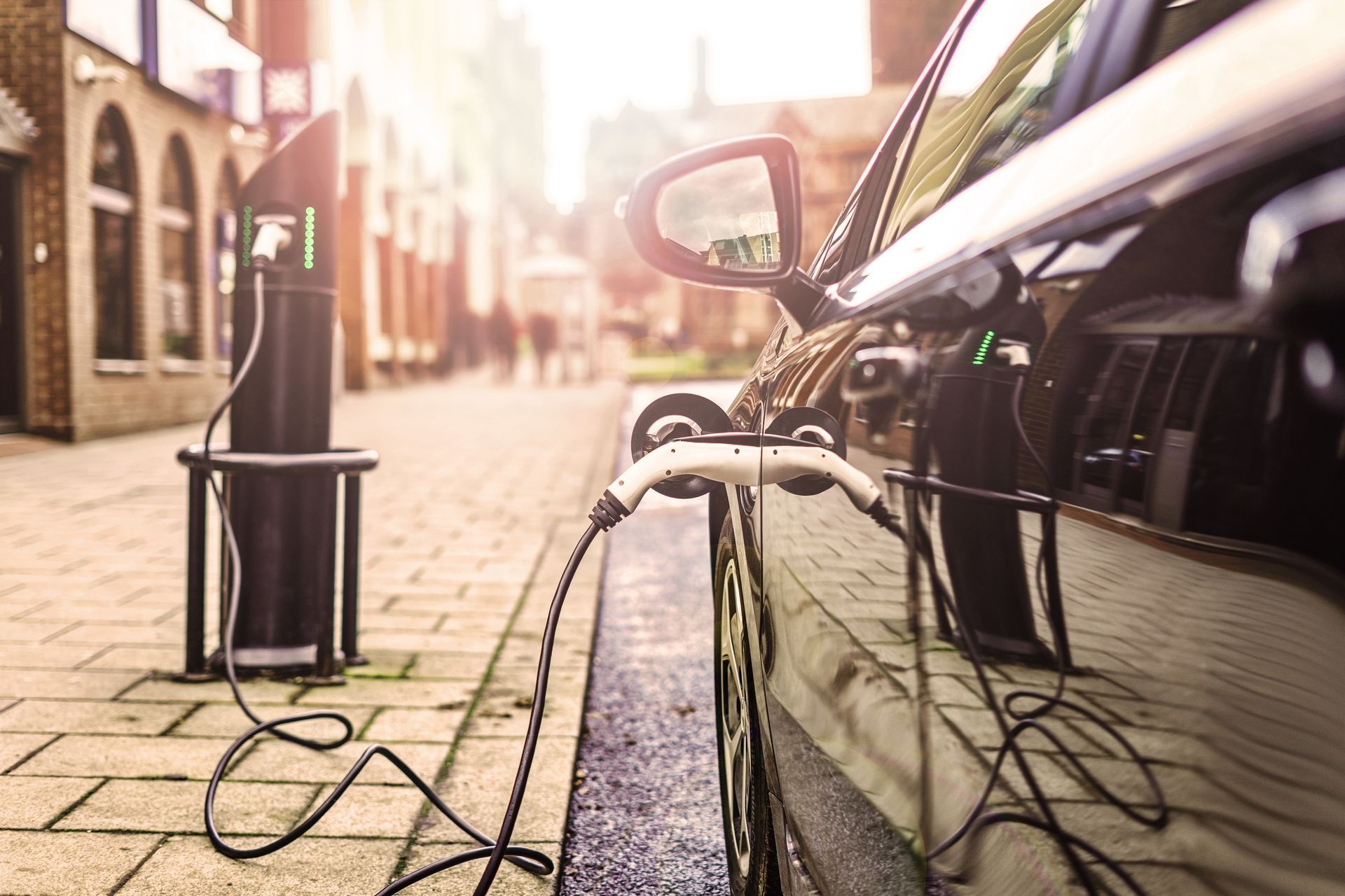 An electric car is being charged at a charging station on the side of the road.
