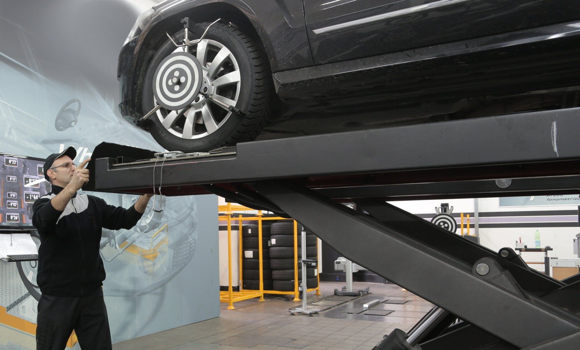 A man is working on a car on a lift in a garage.