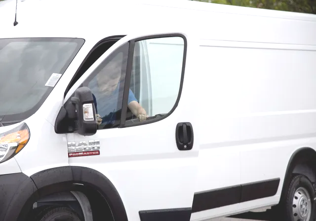 A man is sitting in the driver 's seat of a white van.