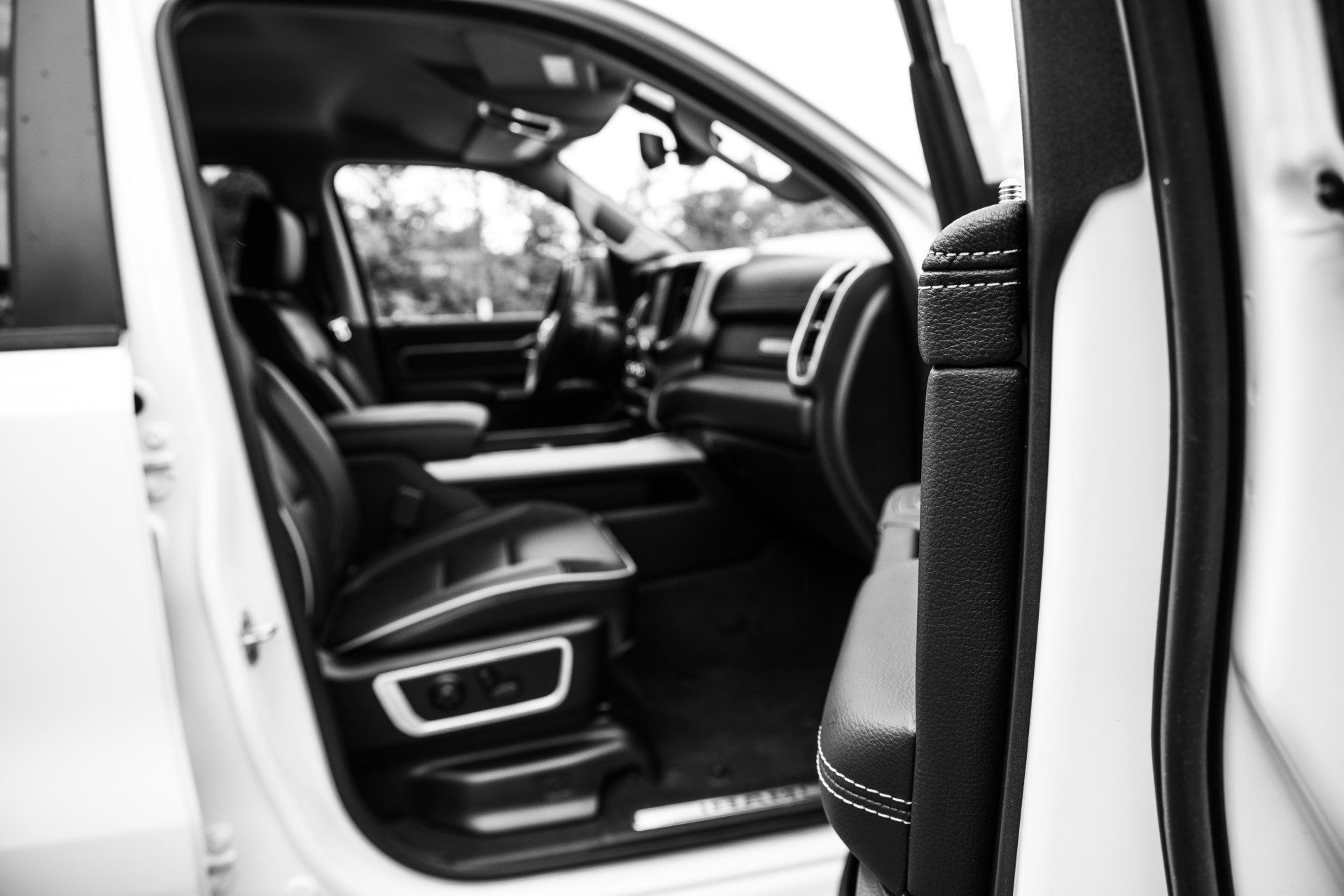 A black and white photo of the inside of a white car with the door open.