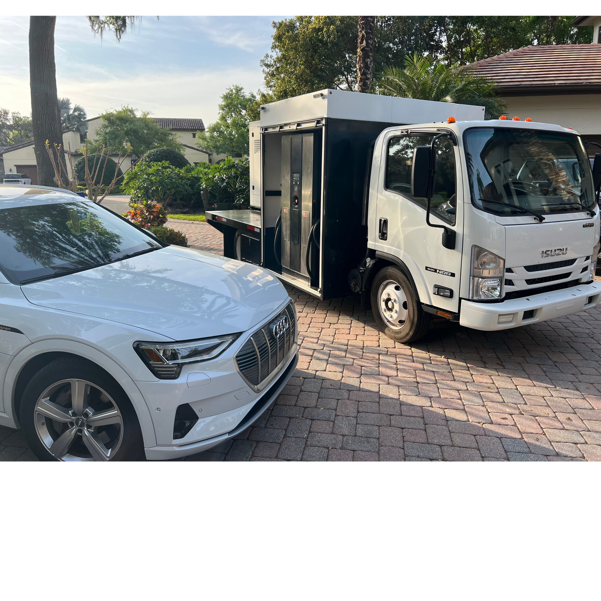 A white car is parked next to a white truck.