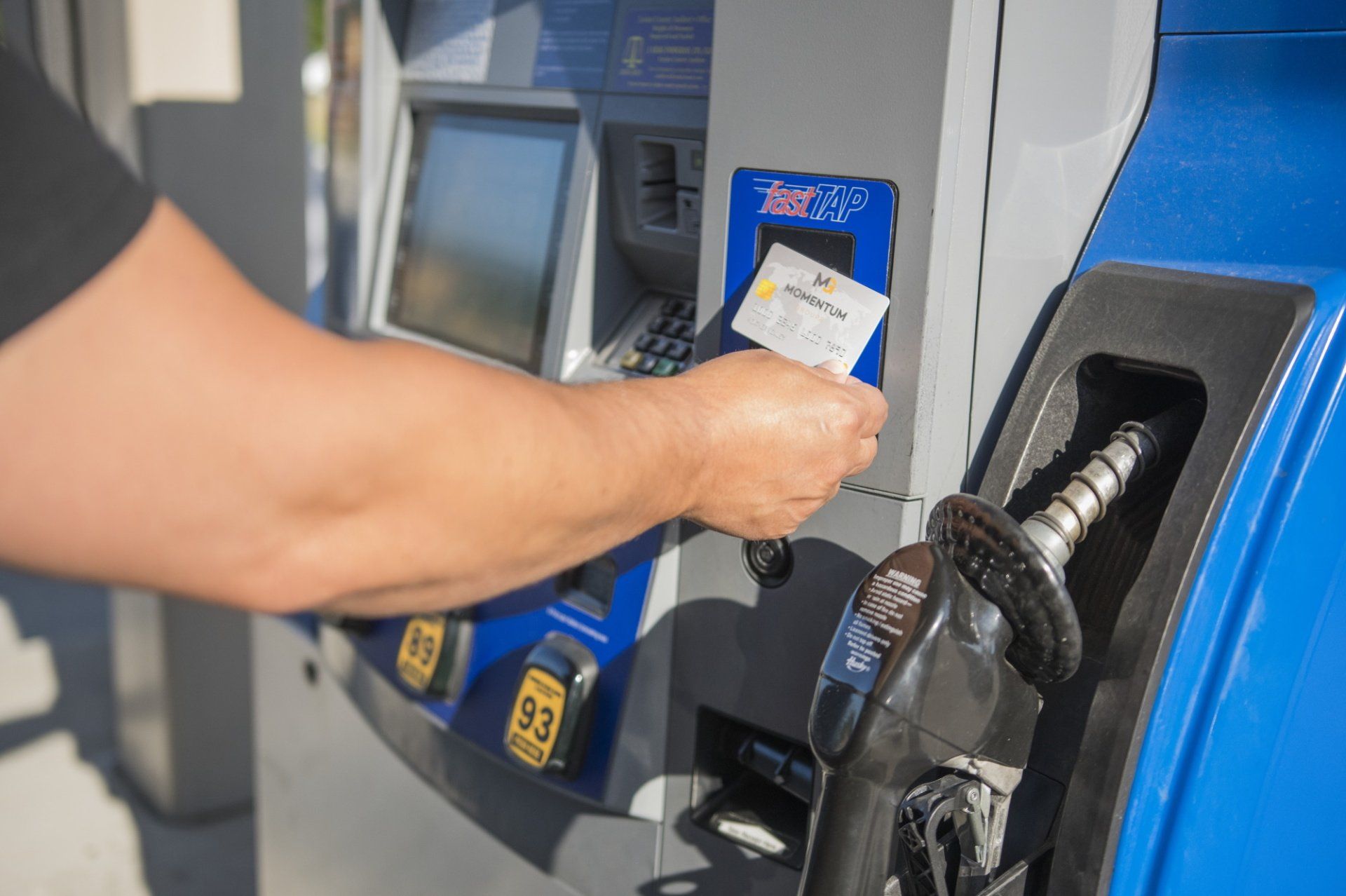 A person is using a credit card to pay for gas at a gas station.