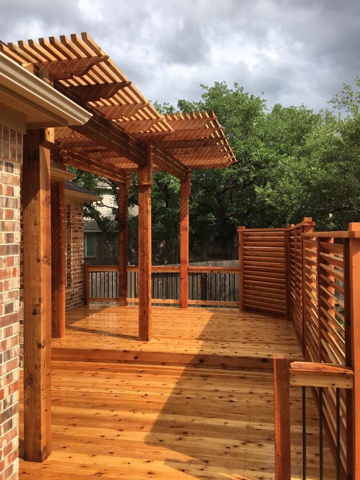 A wooden pergola is sitting under a blue sky in a backyard.