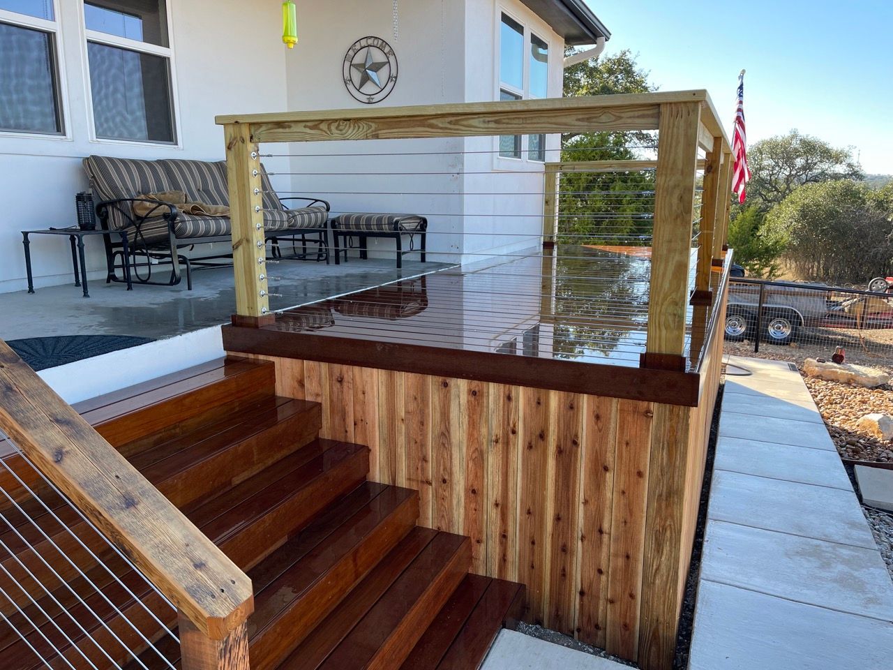 A wooden deck with a railing and trees in the background