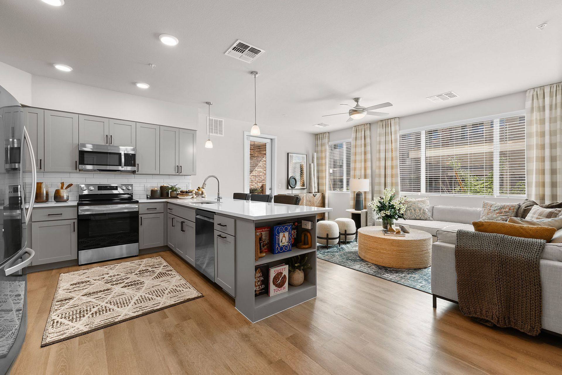 Modern kitchen and living room with gray cabinets, island, and large windows at Marq Bronco Butte, offers apartments in North Phoenix, AZ.