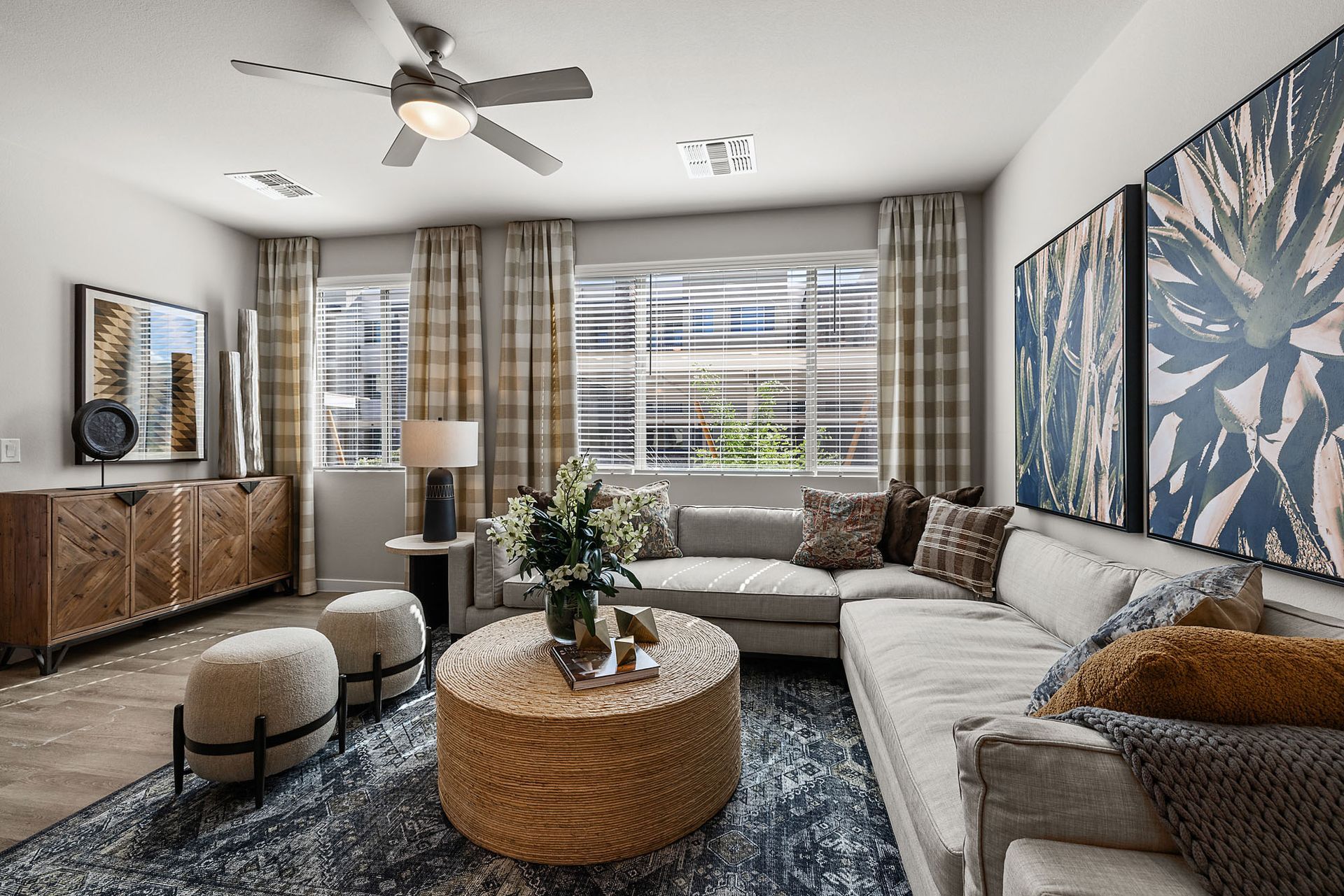 Living room with sectional sofa, coffee table, rug, artwork, and patterned curtains