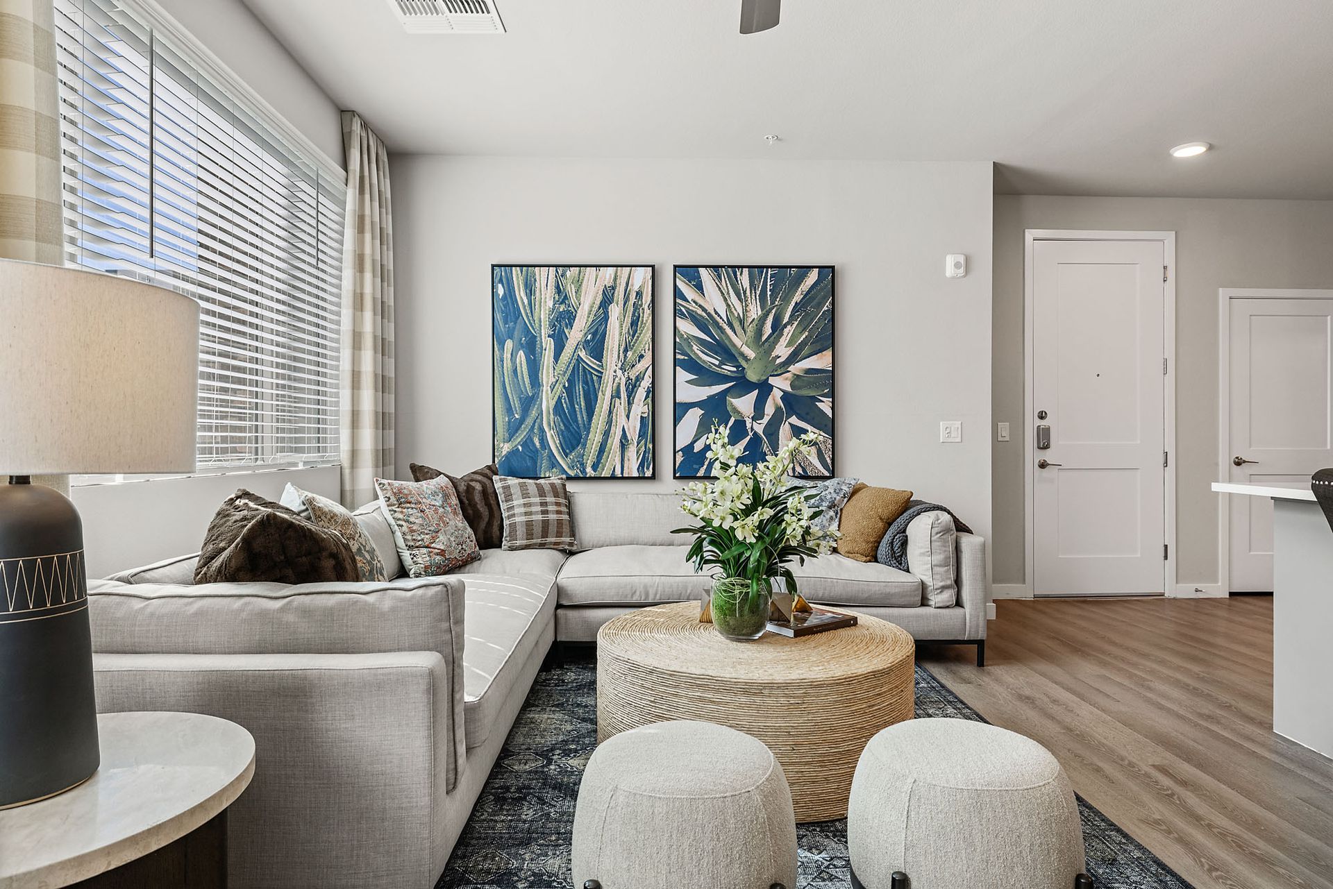 Living room with gray sectional, round coffee table, blue art, and neutral decor at Marq Bronco Butte, offers apartments in North Phoenix, AZ.