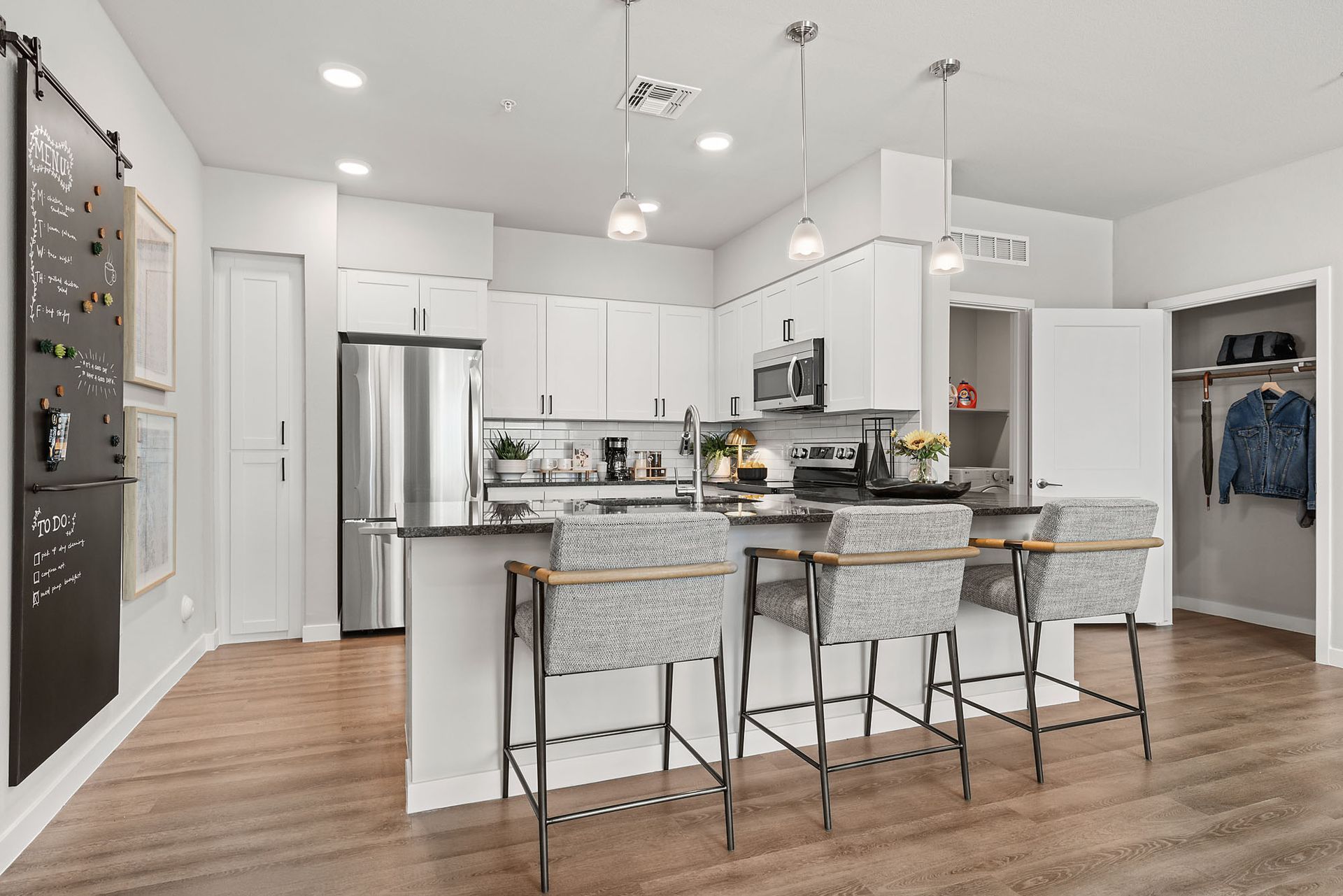 Modern kitchen with white cabinets, island with stools, and stainless steel appliances at Marq Bronco Butte, offers apartments near Phoenix Sonoran Preserve in North Phoenix, AZ.
