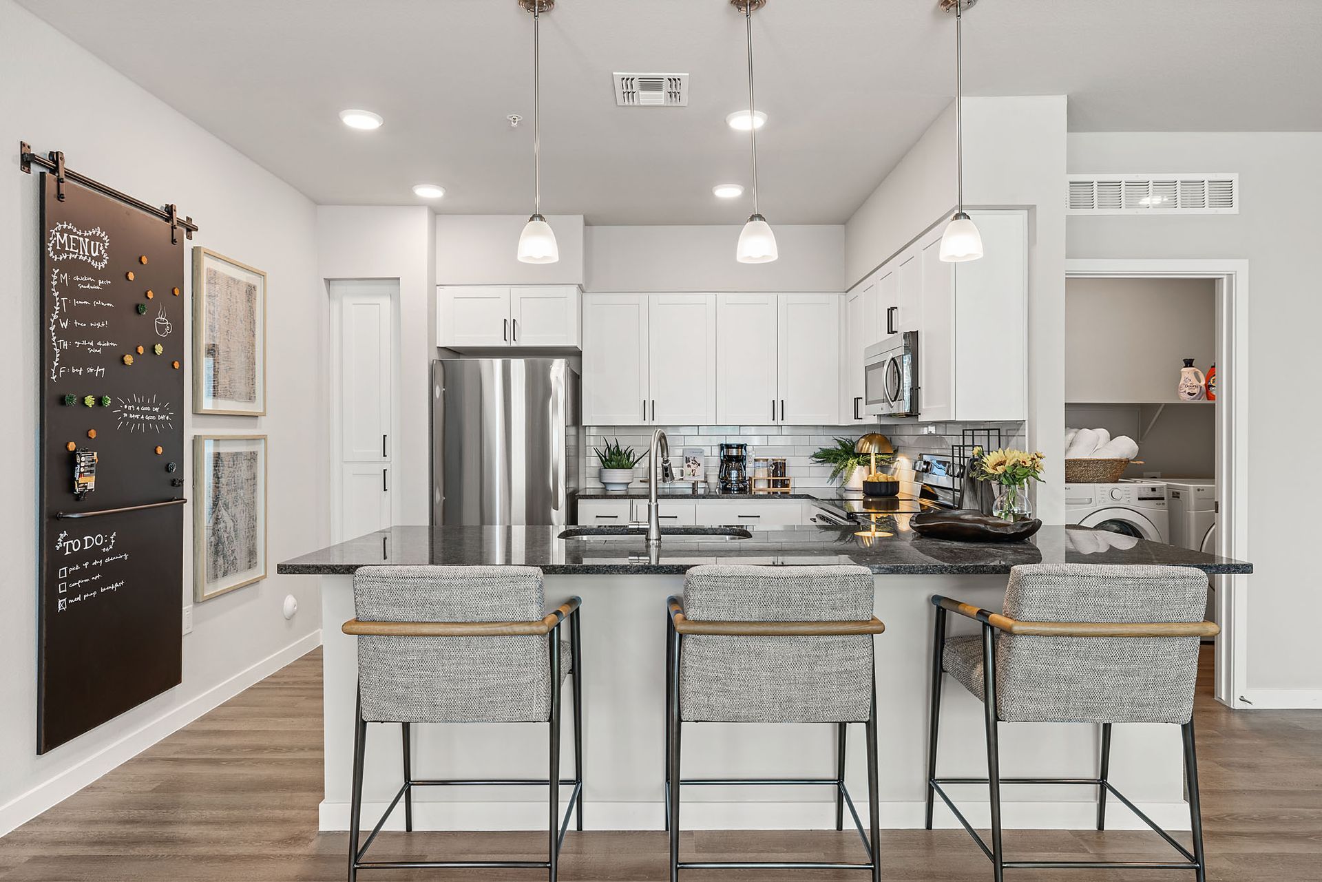 Modern kitchen with island, stainless steel appliances, white cabinets, and bar stools at Marq Bronco Butte, offers apartments near Phoenix Sonoran Preserve in North Phoenix, AZ.