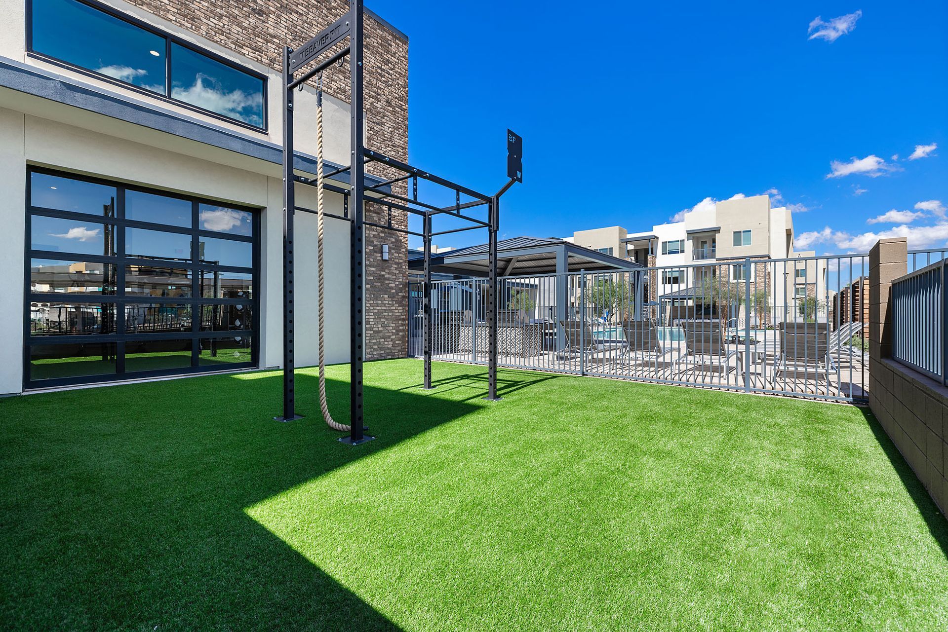 Outdoor fitness area with turf, monkey bars, and a building under a blue sky at Marq Bronco Butte, offers apartments near NAU-North Valley in North Phoenix, AZ.