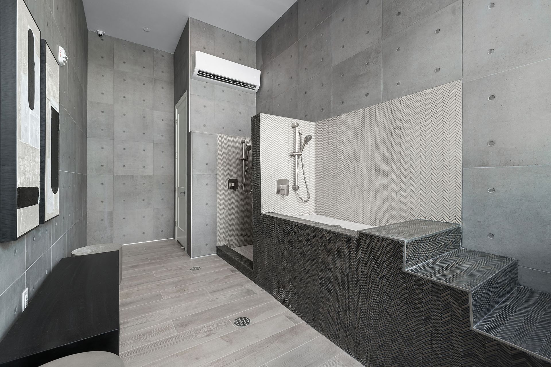 Modern bathroom with concrete walls, wood floors, dark tiled tub, and shower at Marq Bronco Butte, offers apartments near Phoenix Sonoran Preserve in North Phoenix, AZ.