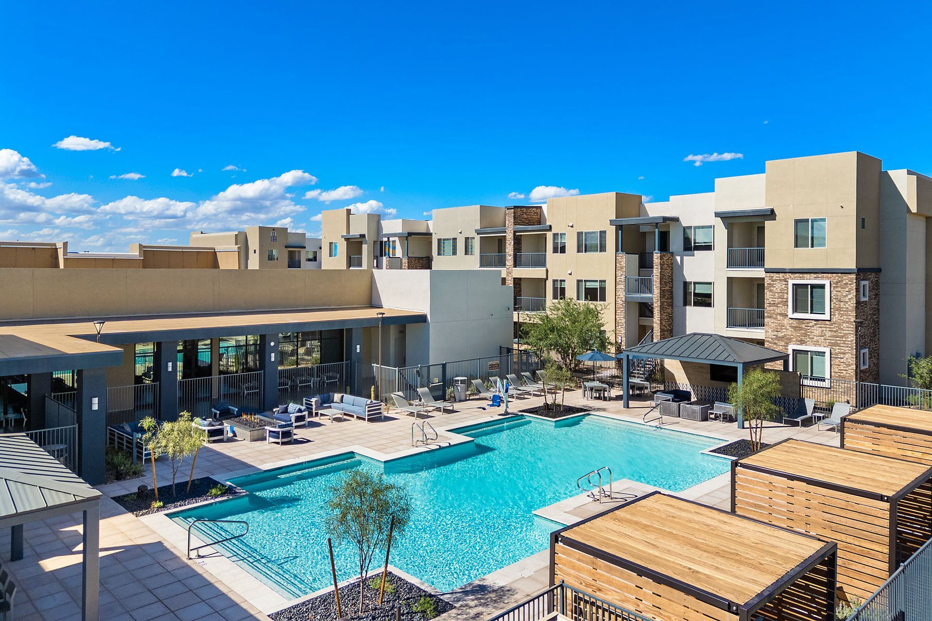Apartment complex with a pool, lounge area, and clear blue sky at Marq Bronco Butte, offers brand-new apartments near USAA in North Phoenix, AZ.