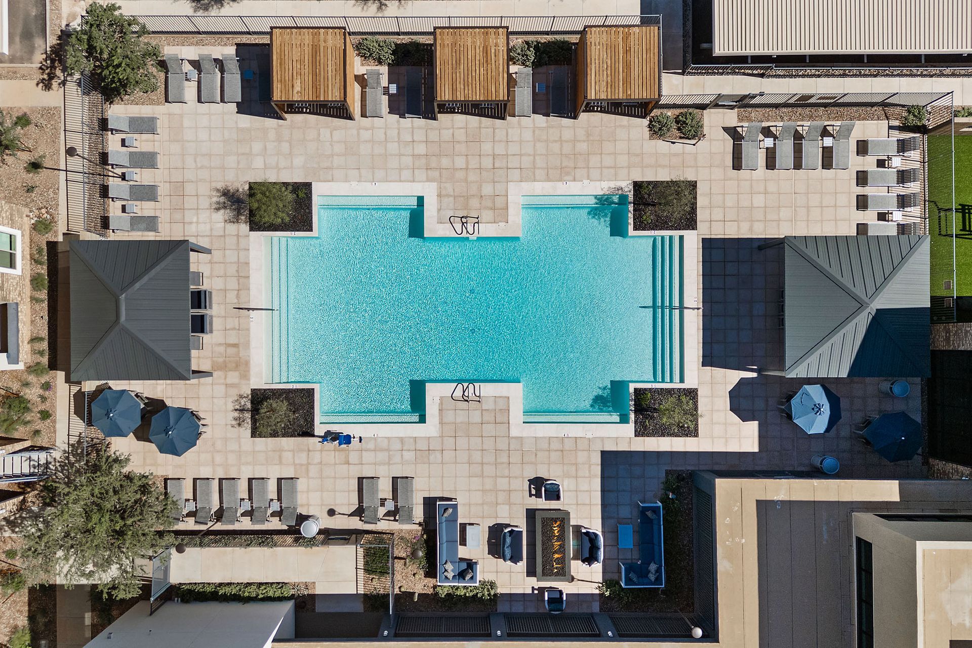 Aerial view of a pool area with a swimming pool, lounge chairs, cabanas, and a gazebo at Marq Bronco Butte, offers brand-new apartments near USAA in North Phoenix, AZ.