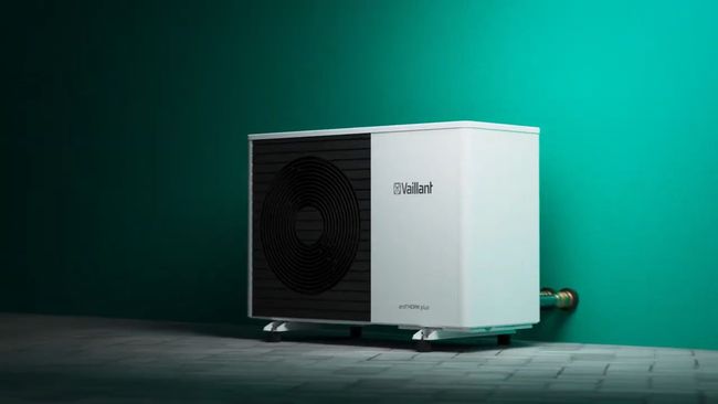 Unità esterna della pompa di calore di colore bianco su un pavimento scuro, contro uno sfondo color verde acqua.
