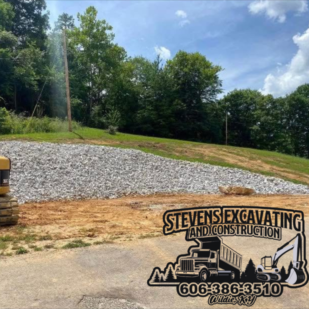 A hillside construction site with gray rocks and a company logo at the bottom.
