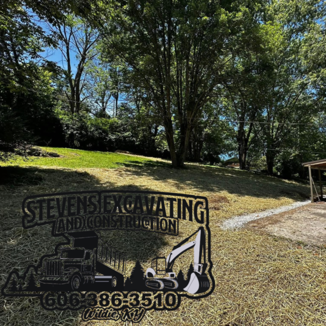 Stevens Excavating sign in a grassy area with trees in the background.