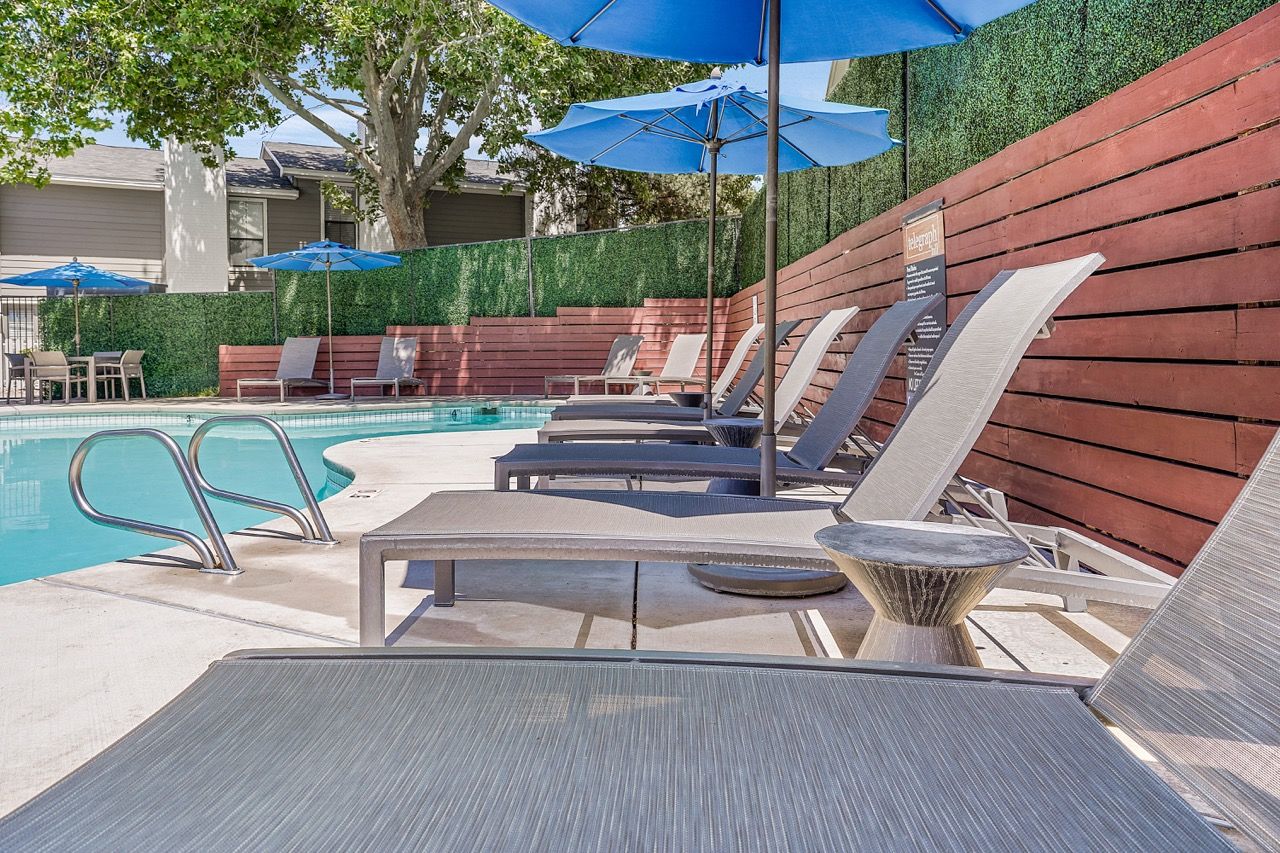 Telegraph Hill  pool area with lounge chairs and blue umbrellas.