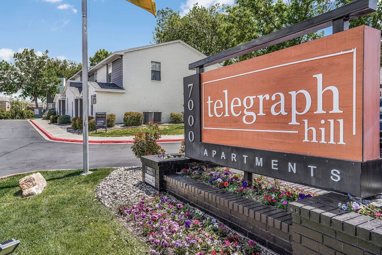 Exterior view of Telegraph Hill Apartments sign with landscaped front yard and building in background.