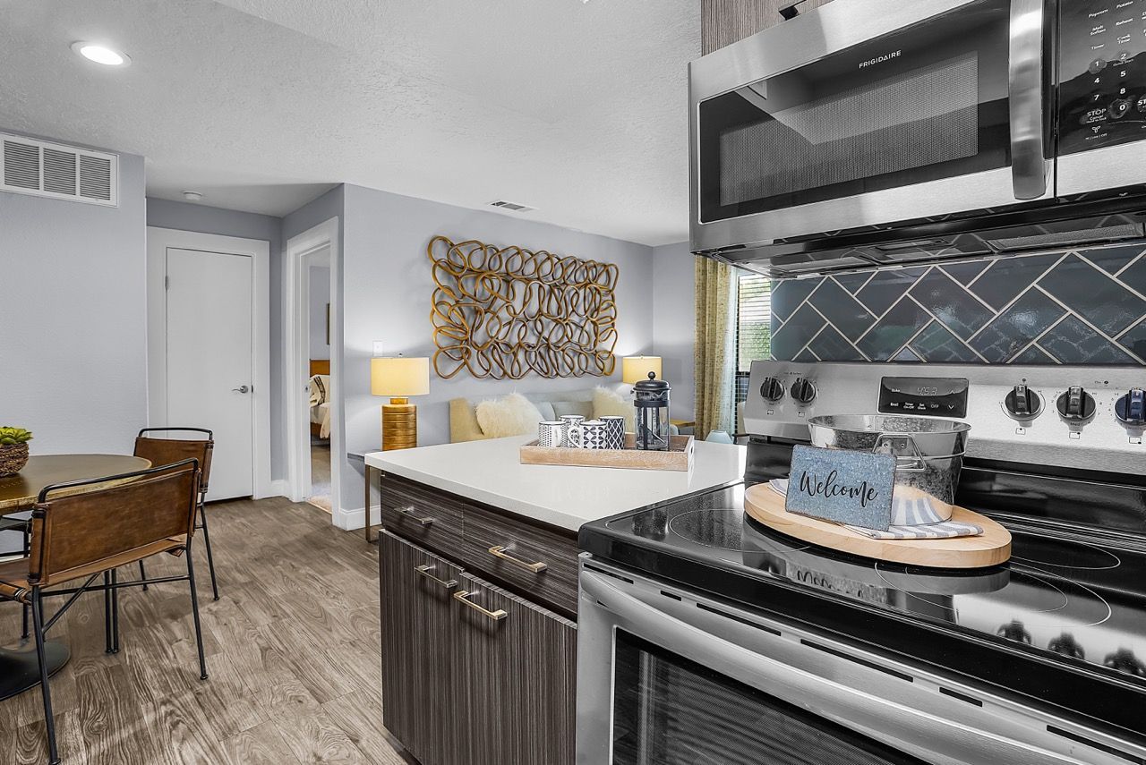 Open-plan kitchen with stainless steel stove and microwave, dark wood cabinets, and a dining table.