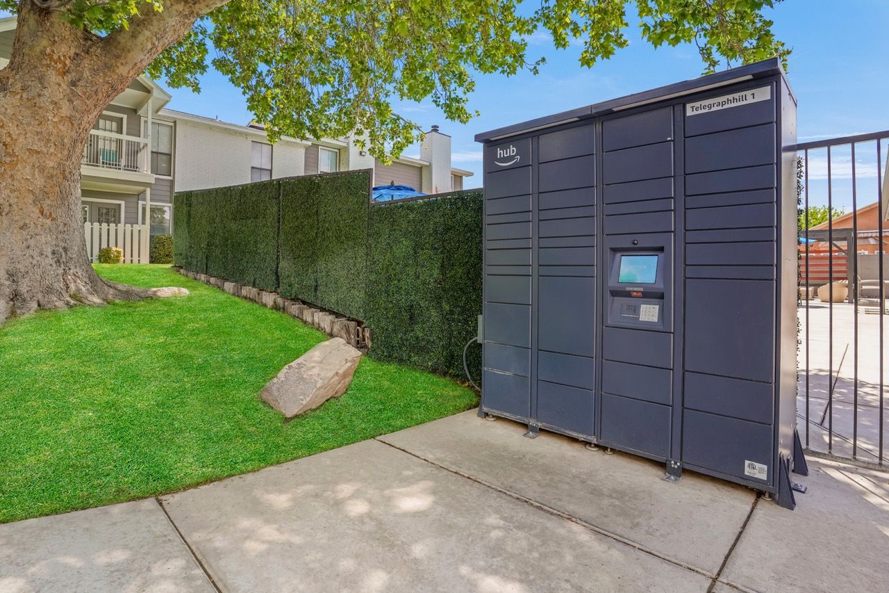 Telegraph Hill parcel locker unit beside a sidewalk with a hedge and tree in a multifamily property.