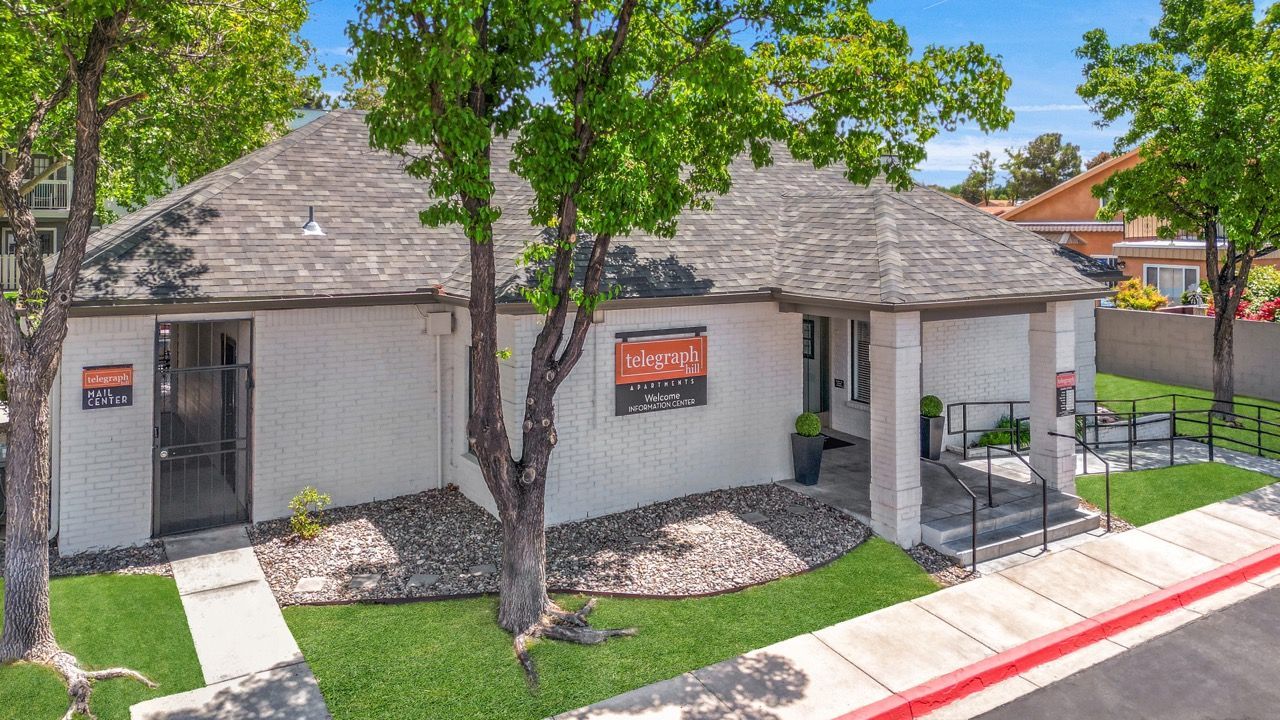 Exterior view of a white brick leasing office with a Telegraph Hill sign, steps, and trees.