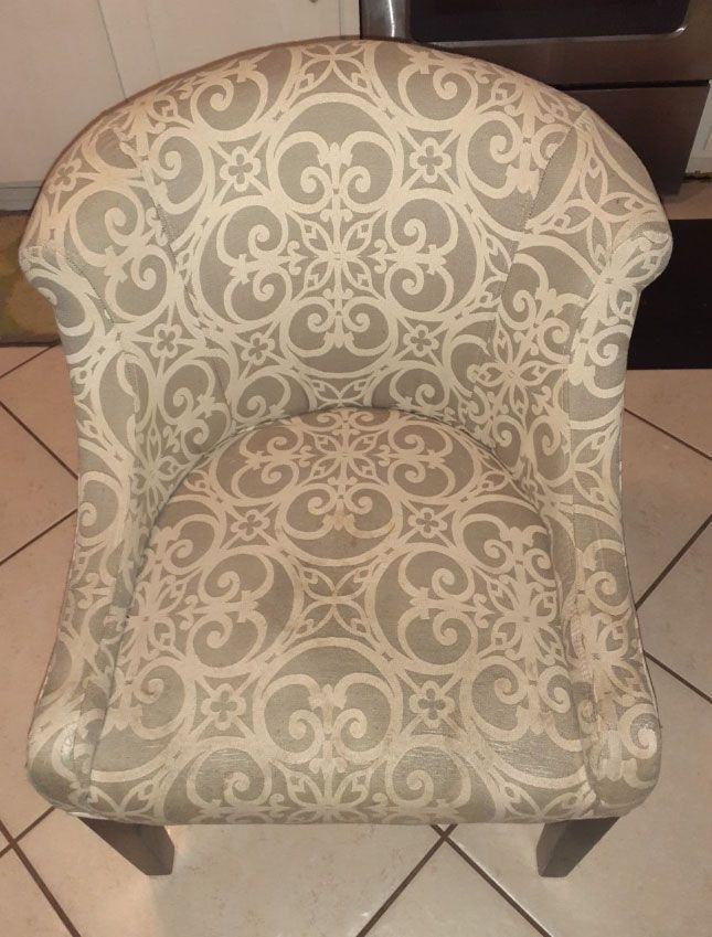 Upholstered armchair with a beige and white patterned design. Dark wood legs.