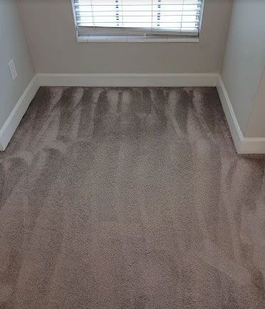 A small, carpeted alcove with a window, light gray walls, and white trim.