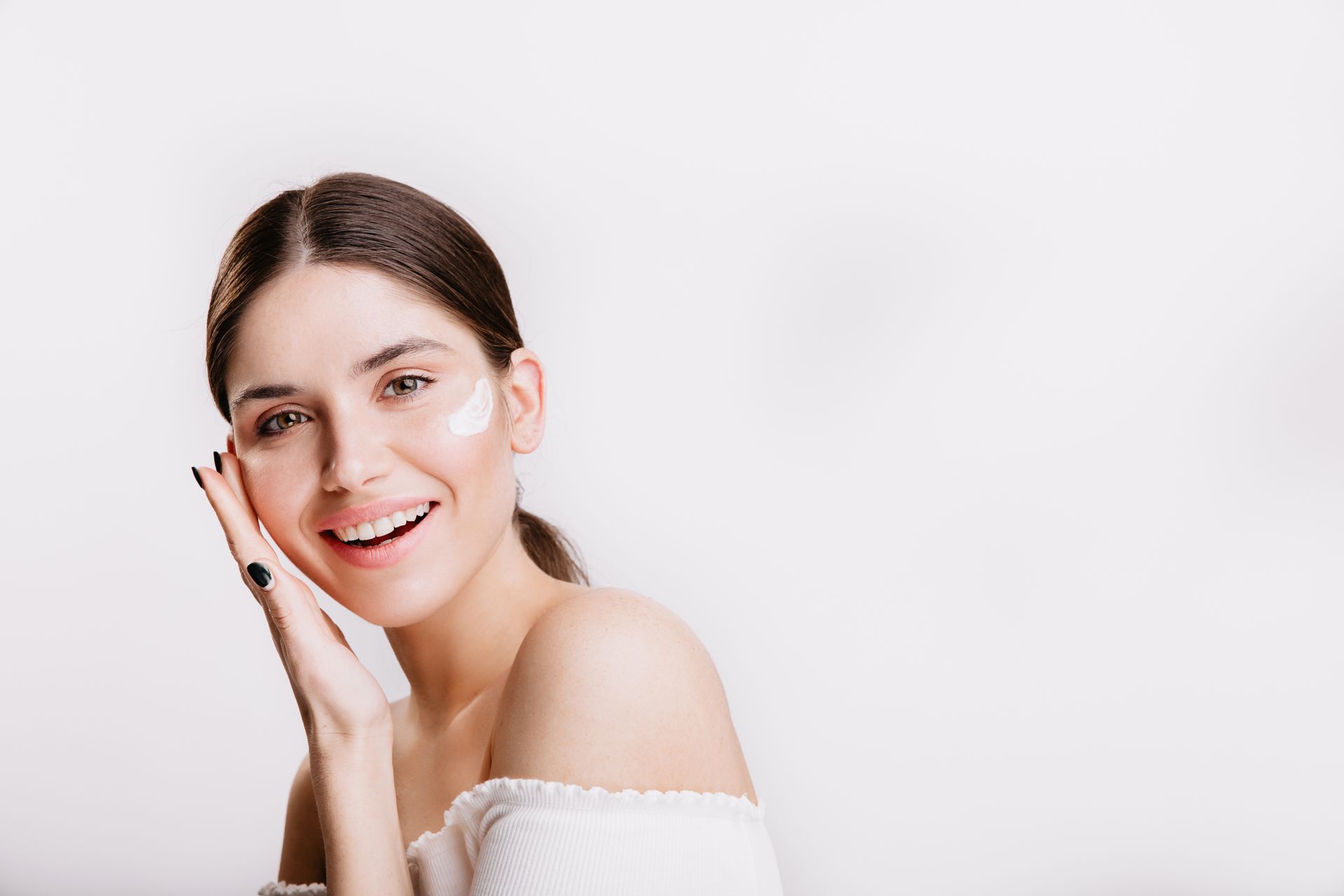 A woman is smiling and touching her face with her hand.