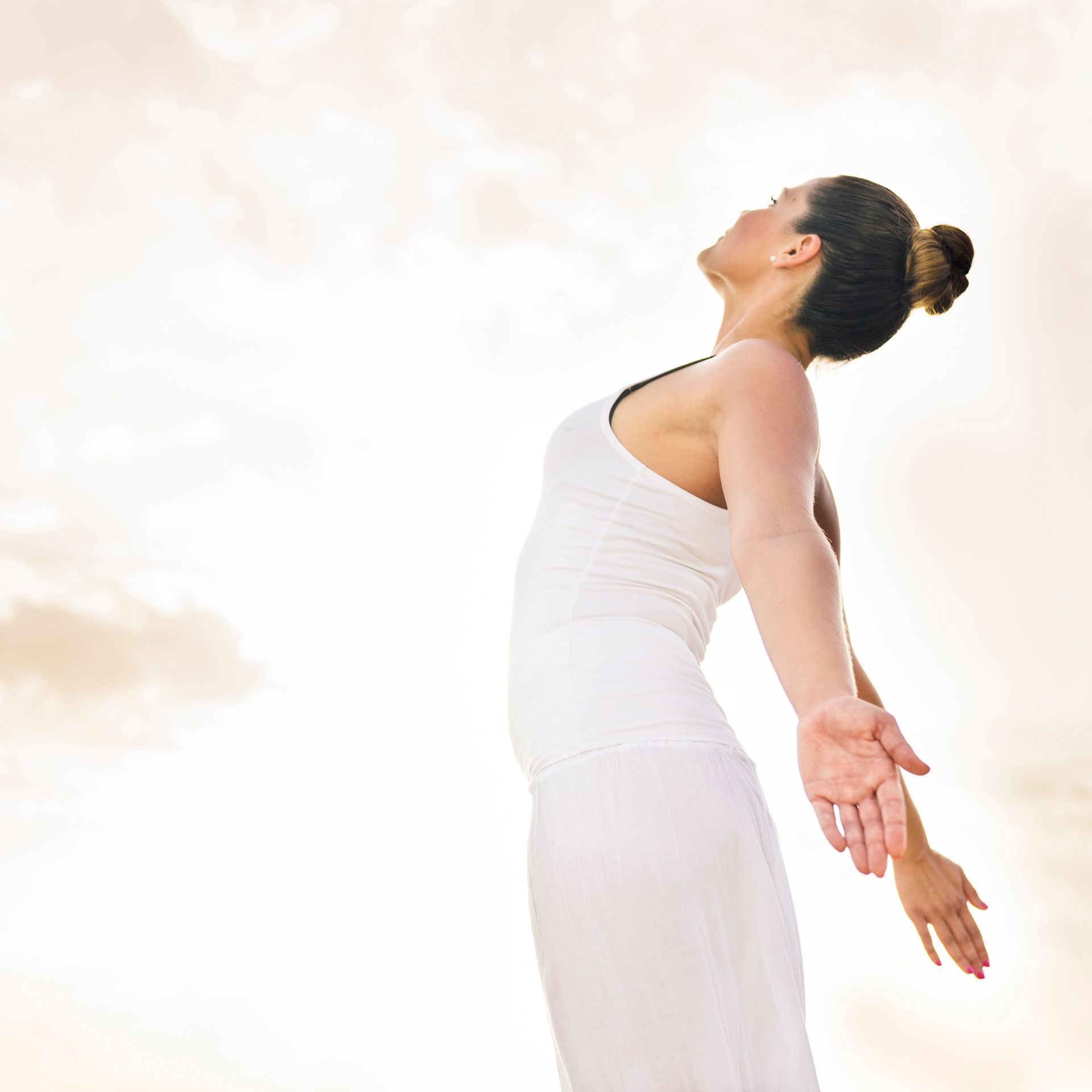 A woman in a white dress with her arms outstretched